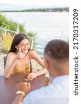 Small photo of A young woman gives a rousing thumbs up gesturing her date is going very well. At an outdoor bar or resto.