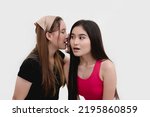 Small photo of A woman shares some juicy secret gossip from the grapevine to her friend, who is gasping from the controversial and intriguing hearsay. Isolated on a white backdrop.