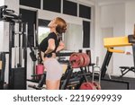 Small photo of A lithe and svelte woman stretching her body while warming up at the gym.
