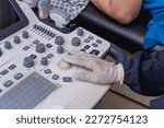 Small photo of A medical sonographer using the trackball of a ultrasound machine at the clinic.