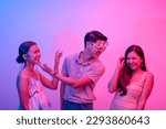 Small photo of A funny playboy flirting simultaneously with two women. Hedonistic lifestyle lit with pink and blue neon colors.