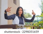 Small photo of A pretty lady wearing a cardigan and navy blue long sleeves top is looking at the camera while being feisty and holding up a rock and roll hand sign.