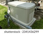 Small photo of A Home Standby Generator installed at the backyard of a house. An air-cooled natural gas or liquid propane generator for residential use.