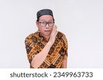 Small photo of A middle aged man whispering secret information. Disclosing rumors or hearsay. Wearing a batik shirt and songkok skull cap. Isolated on a white background.