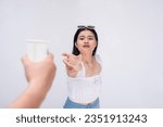 A thirsty asian woman desperately reaches out to someone holding a cup of water. A lady pleading for a drink. Isolated on a white background.