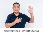 Small photo of A happy middle aged man pledging allegiance with hand raised and other on heart, symbolizing a solemn oath or pledge.