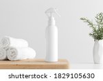 White cosmetic trigger sprayer bottle mockup with towels and a rosemary on a wooden table.