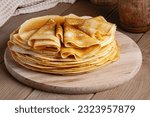 Small photo of Thin pancakes on a wood plate. Homemade crepes, tasty food. Staple of yeast pancakes, traditional for Russian pancake week (Shrove tide). Thin pancake with crispy crust