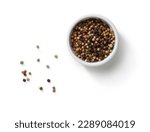 small bowl of peppercorns and scattered peppercorns top view, isolated on white background