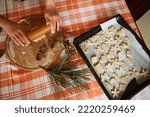 Top view. Selective focus. Housewife's hands roll out dough with a rolling pin, a baking sheet with carved molds of gingerbread dough on the table. Preparing homemade Christmas pastries in the kitchen