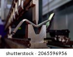 Work on a CNC bending machine in a factory. Sheet metal bending on a high-precision metal bending machine.