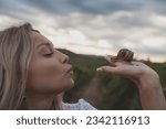 The woman holding snail in vineyard