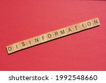 Disinformation, word in wooden alphabet letters isolated on red background with copy space