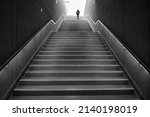 Rear view of an unrecognizable man walking up subway stairs into the light.