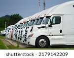 Small photo of La Crosse, Wisconsin USA - July 2nd, 2022: A line of white semi trucks parked together outside.