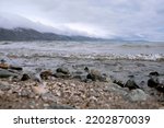 Mountain lake shore. Rocky shore of the reservoir. Mountains with clouds.  Lake Sevan in Armenia.