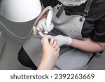 Small photo of The process of filing off a thickened old nail from the fingers of an elderly woman. Procedure podologist.