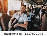 Young Handsome Man Relaxing in Seat of Tour Bus. Attractive Smiling Man Sitting on Passenger Seat of Tourist Bus and Holding Backpack. Traveling and Tourism Concept. Happy Travelers on Trip