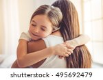 Beautiful young woman and her charming little daughter are hugging and smiling