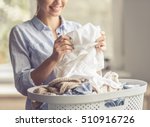 Cropped image of beautiful young woman is smiling while doing laundry at home