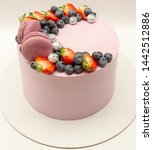 Small photo of licious pink cake decorated with macaroons, strawberries, silver blueberries. On a white background.