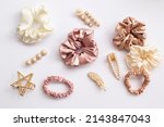 Collection of trendy silk elastic band scrunchies and pearl hair clips on white background. Diy accessories and hairstyles concept, luxury color