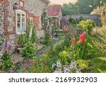 English Country Garden with cottage garden plants in summer and a flint wall