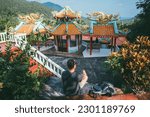 A tourist on an excursion to a mountain temple in Thailand. Young guy visits a small island temple on a mountainside, sightseeing and national architecture