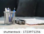 Home office stapler pencils and clipboard with documents and papers on the white table at home or office front view low angle empty lockdown