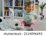 Small photo of one caucasian baby girl making mess in the house playing and mischief with bad behavior ripping paper towel on the floor naughty kid at home childhood and growing up misbehavior concept