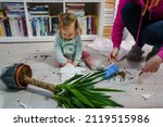 Small photo of one caucasian baby girl making mess playing and mischief with bad behavior ripping paper towel and flower pot crushed on the floor naughty kid at home childhood and growing up misbehavior concept