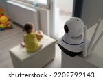 Surveillance camera baby monitor at home monitoring small child while playing in room childhood family protection parenthood concept