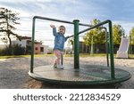 Small photo of One girl small caucasian child female toddler 18 months old in park play in day on speedy spinner merry-go-round turnabout childhood and growing up concept copy space