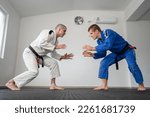 Small photo of Brazilian jiu jitsu bjj training or sparing two athletes fighters dill martial arts technique at gym on the tatami mats wear kimono gi black belt instructor demonstrate technique stand up