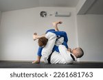 Small photo of Brazilian jiu jitsu bjj training or sparing two athletes fighters dill martial arts technique at gym on the tatami mats wear kimono gi black belt instructor demonstrate submission armbar juji gatame