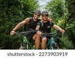 two men portrait of caucasian friends male standing in front of electric bikes e-bike while taking a brake outdoor ride in sunny summer day wear protective helmet