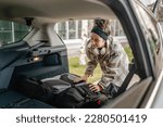 Small photo of One young beautiful woman student travel concept female take luggage baggage suitcase and other stuff and belongings from the back of her car while moving into dormitory on college campus real people