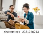 Young caucasian couple woman and man wife and husband or girlfriend and boyfriend opening gifts box presents and read card in front of laptop computer at home having online video call happy copy space