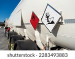 Flammable and environmental contaminant hazard labels on a tank truck with dangerous goods.