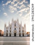 Small photo of Milan, Italy - March 2021: View of the Milan Cathedral with empty square due to the coronavirus blockade, with blue sky with white clouds and glow of light from the newly risen sun, vertical