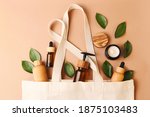 Open eco friendly cotton reusable bag with the different containers from the natural wood and brown glass.Fresh natural leafs around.Concept of organic,zero waste cosmetics.Woman bag with ac?essories.