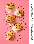 Small photo of Soft, fluffy, chocolate chip vanilla muffins in paper liners, on pink background.