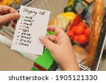 In supermarket, women's hands hold list of products. Person shopping at grocery shop. food concept