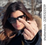 Small photo of Portrait of young woman showing obscene gesture