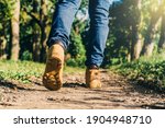 feet of an adult wearing boots to travel walking in a green forest. travel and hiking concept.