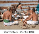 Small photo of Varanasi, Uttar Pradesh, India - 28 January 2012: four scantily clad unidentified men making and eating sweet desserts while talking and sitting cross legged on the steps leading to the Ganges river