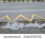 zig zag yellow line on the side of the damaged and flooded asphalt road