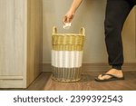 woman throws rubbish in organic waste bin.  The trash can is made of woven bamboo.  plastic free and environmentally friendly waste basket.