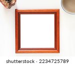 Empty picture frame wooden square shape with coffe cup, and cactus on a white background. Anniversary, valentine, wedding, and mother day concept. Top view, photo frame for template.