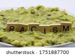 Small photo of Close up of isolated word racism spelled by wooden letters on disgusting green slimy stodge (focus on word center)